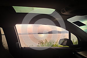 Interior car, mirror, sunroof, ocean, with sunlight reflection and road plants