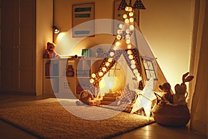 Interior of children`s playroom with tent, lamps and toys in dar