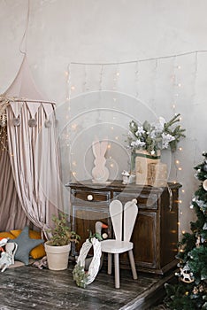 Interior of a children`s room decorated for Christmas. Awning bed with toys and pillows, a tree, a wardrobe and an armchair in