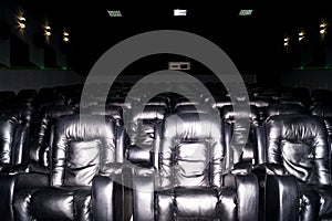 The interior of a cinema hall with black leather seats. The film does not show and no people