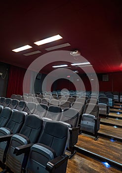 Interior of a cinema hall with projector handing on the ceiling, Empty cinema hall seats, comfortable and soft chairs. Perspective