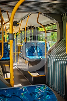 Interior of a city bus. Empty bus interior. Bus with blue seats and yellow handrails