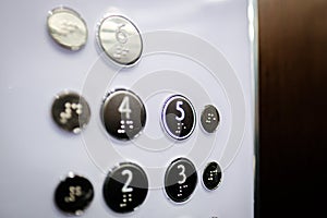 Interior and closeup of metal buttons in elevator. Level 5 is highlighted. Selective focus