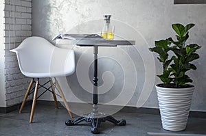 Interior in the coffee house. White table and chair in the corner of the cafe with tea on the table.