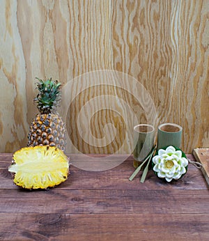 Interior composition of a home on wood table or floor and wall. Handmade white lotus aroma candle. Tropical fruit fresh pineapple