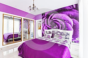 Interior of cozy bedroom in bright violet tones. Large mirrored