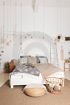 Interior of cozy and bright bedroom. Bed with white, beige and grey bedclothes