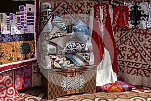 Interior decoration of a traditional nomad house yurt - a chest, pillows and blankets, felt carpets, clothes photo