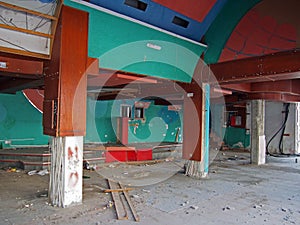 The interior of a derelict abandoned discotheque or nightclub with rubble covered floor and wired hanging from many coloured paint