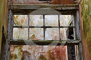 Interior of derelict building with broken window, peeling paint and mould on walls