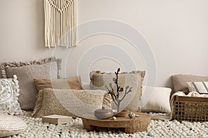 Interior design of cozy composition of meditation living room interior with beige carpet, pillows, macrame and personal