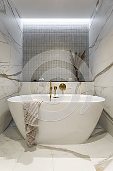 Interior design of elegant bathroom with gold tape, blue and pink tiles, classic white bath, toilet seat, silk, brown wase with
