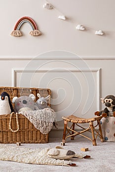 Interior design of kids room interior with wicker basket, plush animal toys, poster, wooden blockers, ladder, white stool, beige