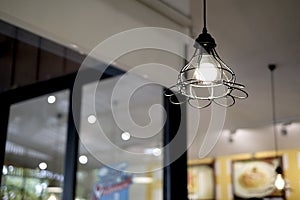 Interior design of lamp. A LED light bulb is illuminating and hanging under a house roof. Lighting lamp under the ceiling