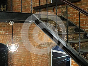 Interior design of lamp. A light bulb is illuminating and hanging under a house roof and an old cast iron staircase