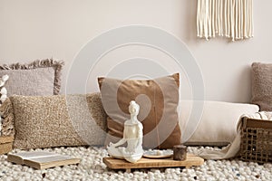 Interior design of meditation living room interior with beige carpet, pillows, macrame and personal accessories. Home decor.