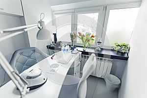 interior design of a nail studio, light room with light color furniture and flowers on the window-sill