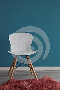 Interior design scene with a modern white chair on blue wall