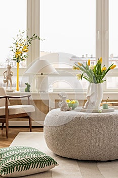 Interior design of spring living room with design sofa, furniture, vase with tulips, easter decorations
