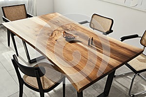 Interior design of stylish dining room interior with family wooden table, modern chairs, plate with nuts, salt and pepper shakers.