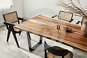 Interior design of stylish dining room interior with family wooden table, modern chairs, plate with nuts, salt and pepper shakers.