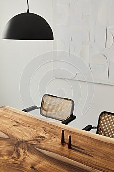 Interior design of stylish dining room interior with family wooden table, modern chairs, plate with nuts, salt and pepper shakers.