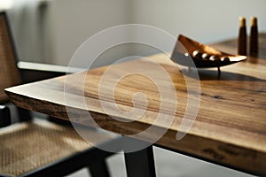 Interior design of stylish dining room interior with family wooden table, modern chairs, plate with nuts, salt and pepper shakers.