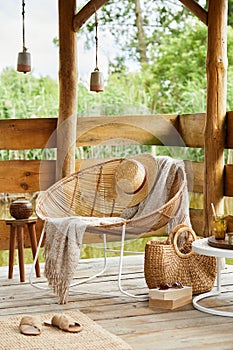 Interior design of summer gazebo by the lake with stylish rattan armchair, coffee table, sofa, pillows, plaid, elegant.