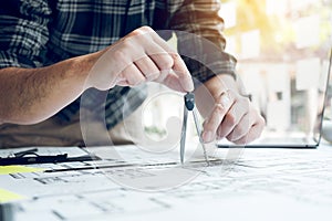 Interior designer or architect reviewing blueprints and holding pencil drawing on desk at home office