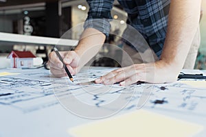 Interior designer or architect reviewing blueprints and holding pencil drawing on desk at home office