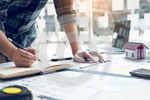 Interior designer or architect reviewing blueprints and holding pencil drawing on desk at home office