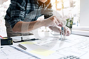 Interior designer or architect reviewing blueprints and holding pencil drawing on desk at home office