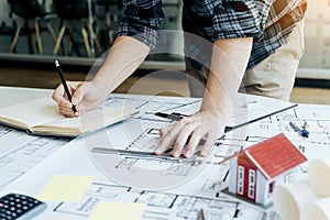 Interior designer or architect reviewing blueprints and holding pencil drawing on desk at home office