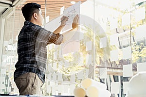 Interior designer or architect reviewing blueprints and holding pencil drawing on desk at home office