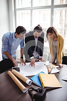 Interior designer with coworkers looking at blueprint