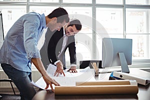 Interior designer discussing blueprint with colleague