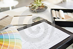 Interior designer's working table, an architectural plan of the house, a color palette.