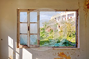 Interior of a desolated house and a window frame with broken glass photo