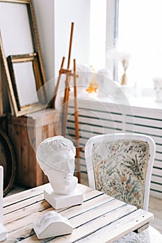 Interior details of home creative studio large wooden table easel and canvases