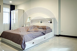 Interior of elegant fancy creamy white tone bedroom with double bed, bed wardrobe and mirror set, brown tone mattress set