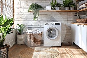 Interior of elegant laundry room in a modern house. White cabinets, wooden tabletop, washing machine, laundry basket