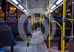 Interior of an empty collective bus at night seen from the bottom chairs