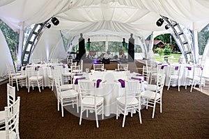 Interior of a event tent decoration ready for guests. Served round banquet table outdoor in marquee