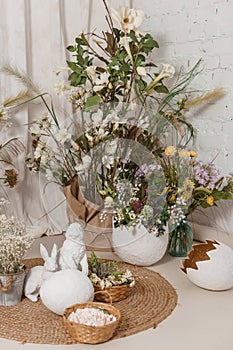 Interior floral Easter composition. Figurines of Easter bunnies and a large eggshell.