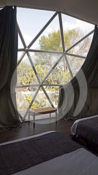 Interior of a geodesic glamping tent with beds and transparent roof to see the sky and stars