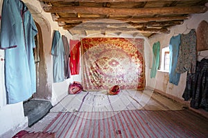 Interior of a historic room decorated with Berber carpet and clothes in Ait Ben Haddou, Morocco