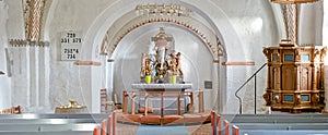 Interior of a historical church with rows of benches, a pulpit, nave or alter with kneeler cushions and sacred figure of