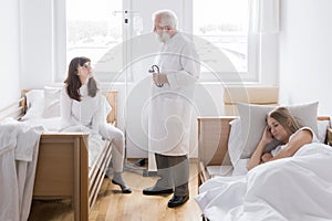 Interior of the hospital room in which the doctor and patients on beds are located
