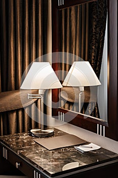 Interior hotel apartment, comfortable room, mirror and desk. folder for notes and lamp standing on a table in a hotel