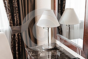 Interior hotel apartment, comfortable room, mirror and desk. folder for notes and lamp standing on a table in a hotel